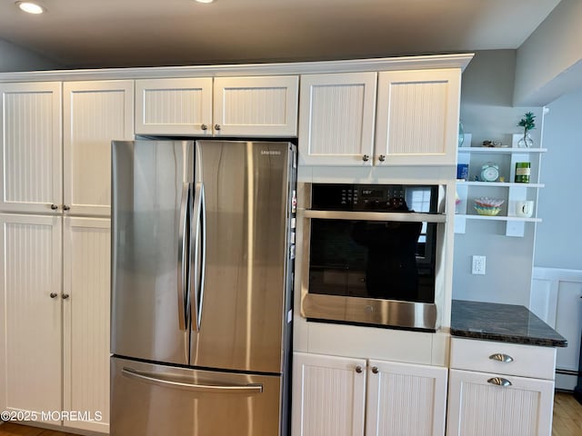 kitchen featuring stainless steel appliances, dark stone countertops, open shelves, and white cabinets