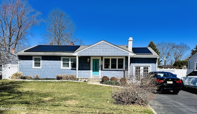 991 Stamler Dr, Toms River, NJ 08753 - view of front facade featuring roof mounted solar panels, a front yard, a chimney, and fence