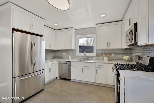 kitchen featuring stainless steel appliances, white cabinets, a sink, and tasteful backsplash