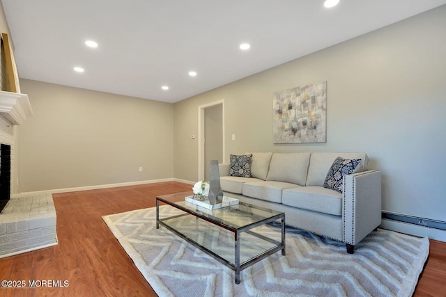 living area with baseboards, a brick fireplace, wood finished floors, and recessed lighting