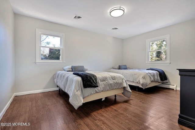 bedroom featuring visible vents, multiple windows, and wood finished floors