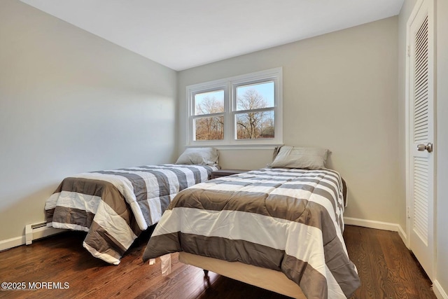 bedroom featuring baseboard heating, wood finished floors, and baseboards