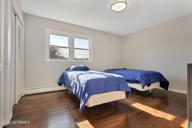 bedroom featuring a baseboard radiator, a closet, baseboards, and wood finished floors