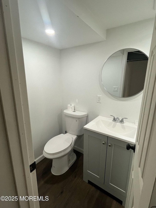 bathroom with toilet, baseboards, wood finished floors, and vanity