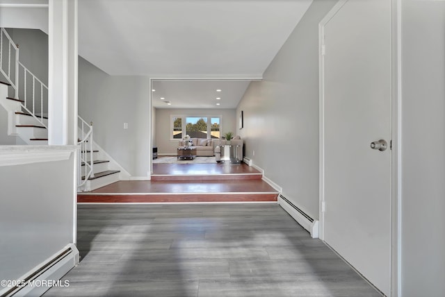 entrance foyer featuring baseboards, stairs, a baseboard heating unit, and wood finished floors