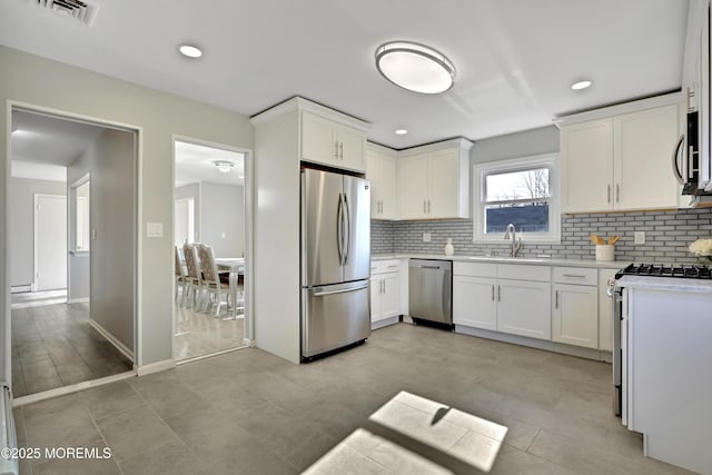 kitchen with visible vents, a sink, stainless steel appliances, light countertops, and backsplash