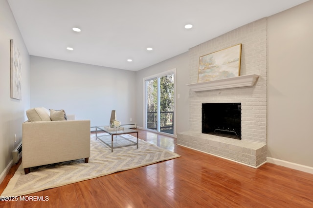 living room featuring recessed lighting, a fireplace, wood finished floors, baseboards, and baseboard heating