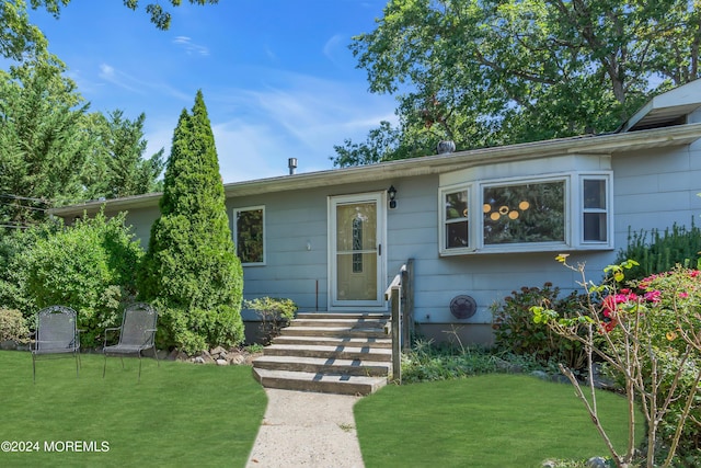 view of front of house with entry steps and a front lawn