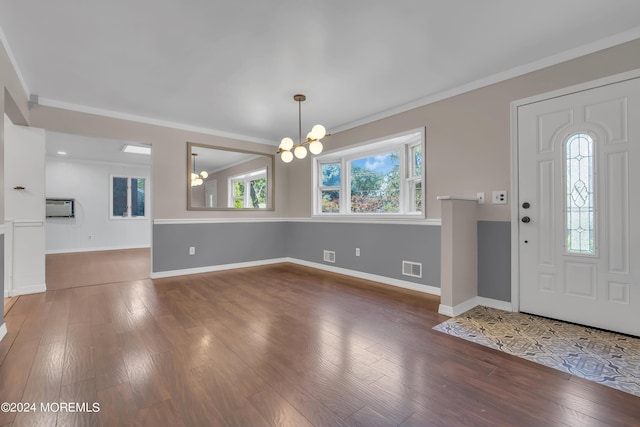 foyer entrance with crown molding, wood-type flooring, visible vents, an inviting chandelier, and a wall mounted air conditioner