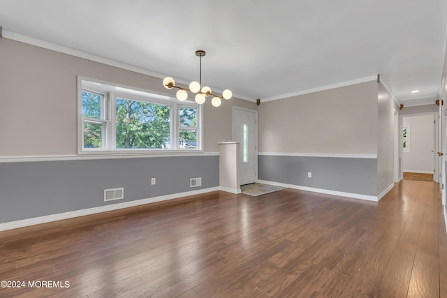 spare room featuring a notable chandelier, visible vents, and wood finished floors