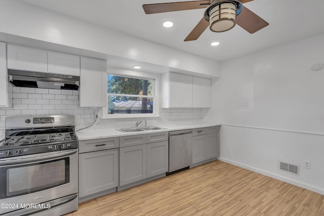 kitchen featuring visible vents, appliances with stainless steel finishes, gray cabinetry, under cabinet range hood, and a sink