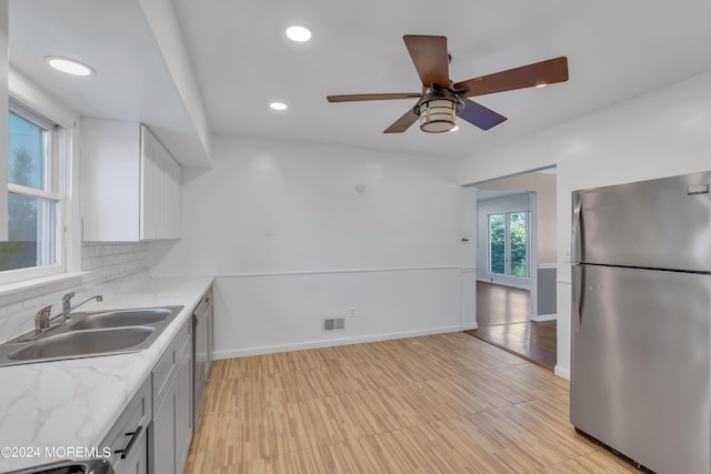 kitchen with a sink, visible vents, baseboards, appliances with stainless steel finishes, and backsplash