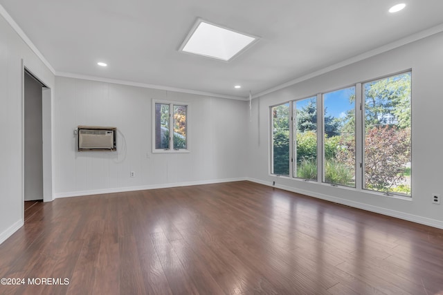 unfurnished room featuring a skylight, baseboards, dark wood-style floors, ornamental molding, and a wall mounted AC