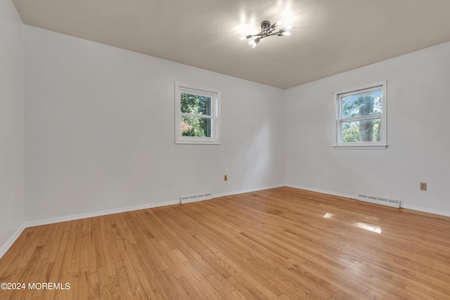 unfurnished room with light wood-style flooring, visible vents, and baseboards