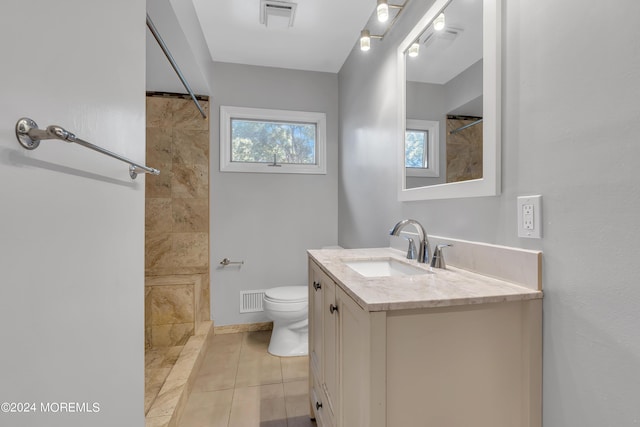 full bath featuring toilet, vanity, a tile shower, and visible vents