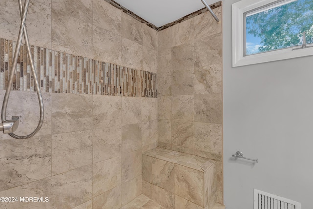 interior details featuring tiled shower and visible vents