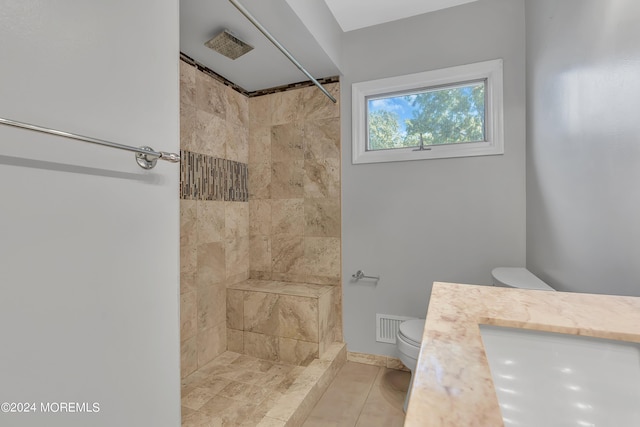 full bathroom with visible vents, vanity, a tile shower, and toilet