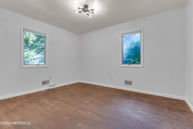 empty room with baseboards, visible vents, and wood finished floors