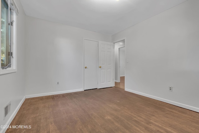 spare room with baseboards, visible vents, and wood finished floors