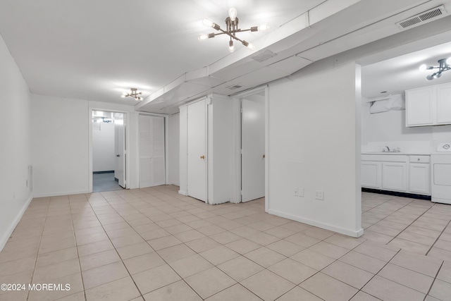 finished below grade area with baseboards, visible vents, washer / clothes dryer, a sink, and light tile patterned flooring