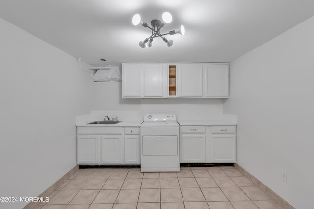 laundry area with cabinet space, light tile patterned floors, baseboards, washer / clothes dryer, and a sink