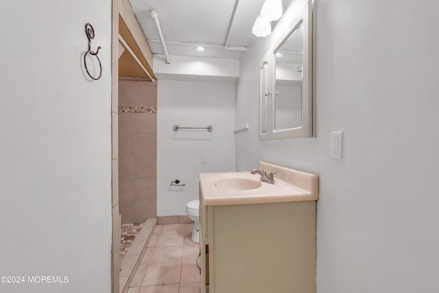 full bath featuring toilet, tile patterned flooring, tiled shower, and vanity