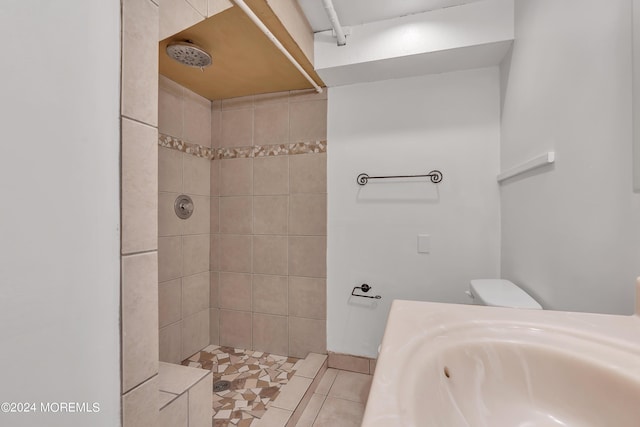 bathroom with a sink, tile patterned flooring, toilet, and tiled shower