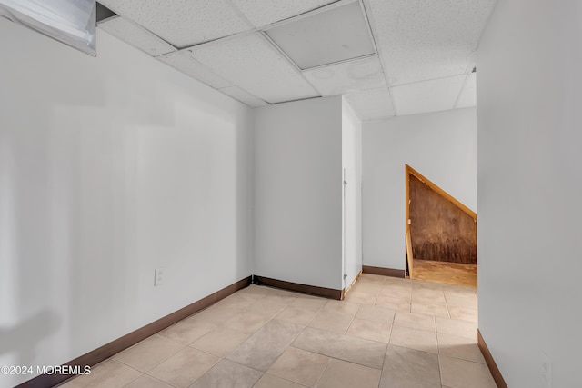 unfurnished room featuring light tile patterned flooring, a paneled ceiling, and baseboards