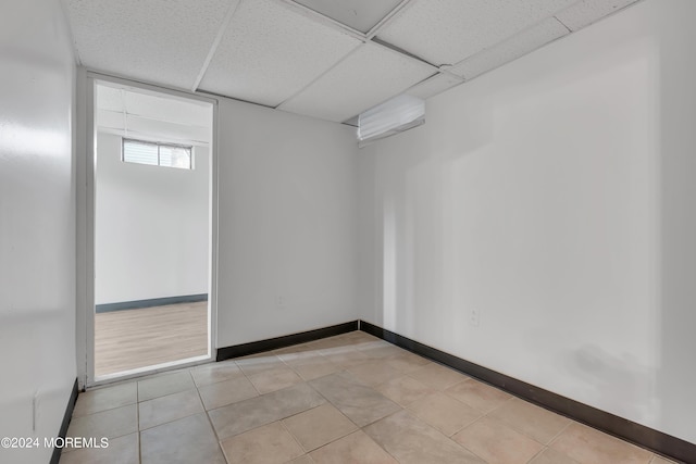 spare room featuring a drop ceiling, baseboards, and light tile patterned flooring