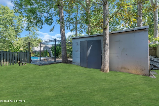 view of yard with a fenced in pool, an outbuilding, a fenced backyard, and a storage unit