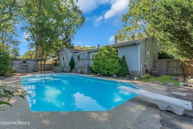 view of swimming pool with fence, a diving board, a fenced in pool, and a patio