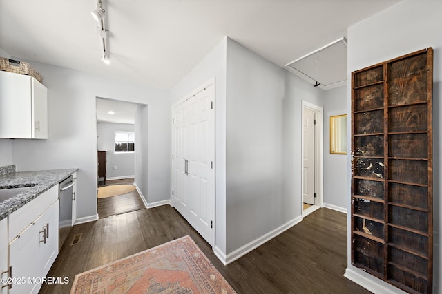 kitchen with baseboards, light stone counters, dark wood-style flooring, white cabinetry, and stainless steel dishwasher