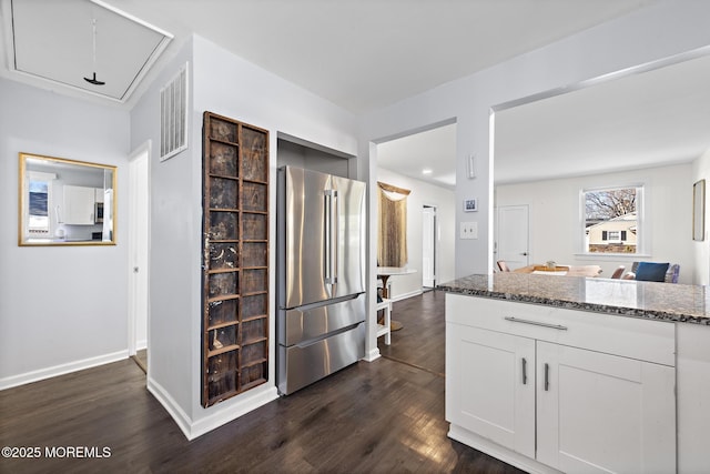 kitchen with dark wood-style flooring, visible vents, appliances with stainless steel finishes, white cabinetry, and dark stone counters