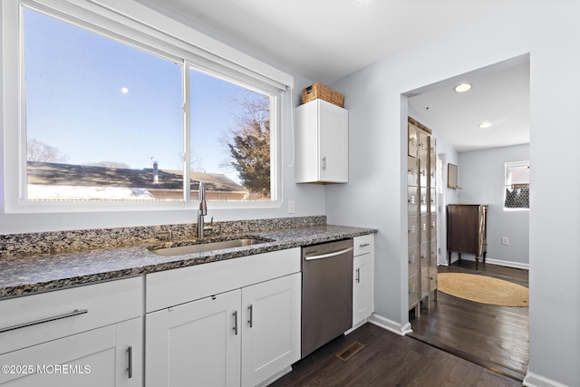 kitchen featuring dishwasher, dark stone countertops, dark wood-style flooring, white cabinetry, and a sink