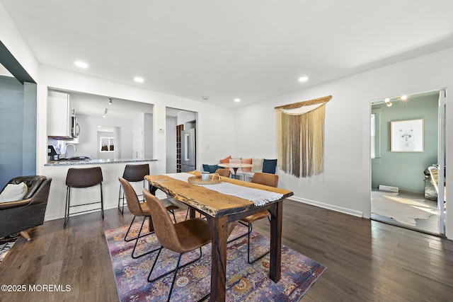 dining area featuring baseboards, dark wood finished floors, and recessed lighting