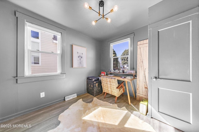 office area featuring an inviting chandelier, baseboards, visible vents, and wood finished floors