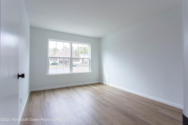 spare room featuring baseboards and wood finished floors