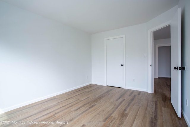 unfurnished bedroom with a closet, baseboards, and wood finished floors