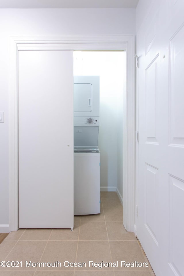 washroom with light tile patterned floors, laundry area, and stacked washer / drying machine