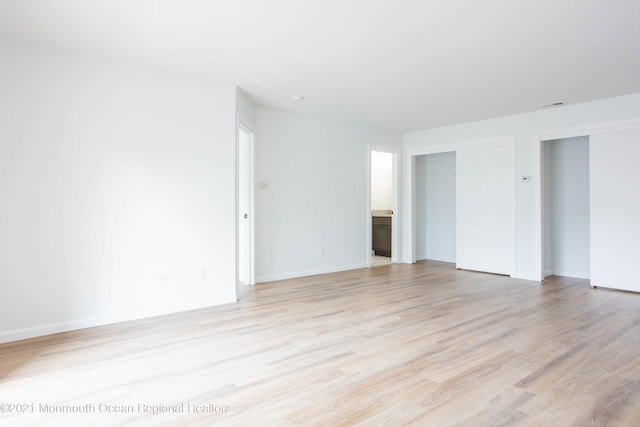 unfurnished room featuring visible vents, light wood-style flooring, and baseboards