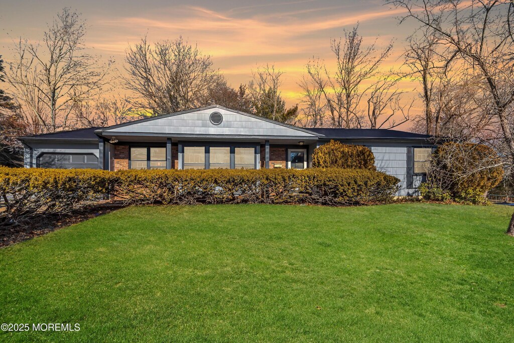 view of front of home with brick siding and a yard