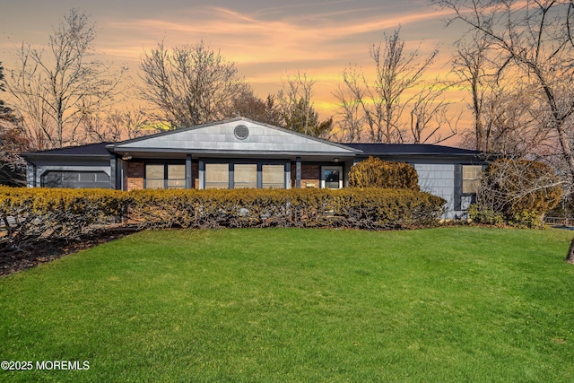 view of front of home with brick siding and a yard