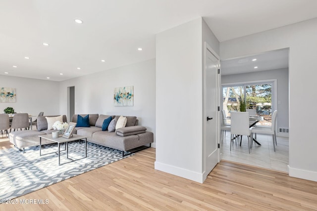 living area featuring baseboards, recessed lighting, visible vents, and light wood-style floors