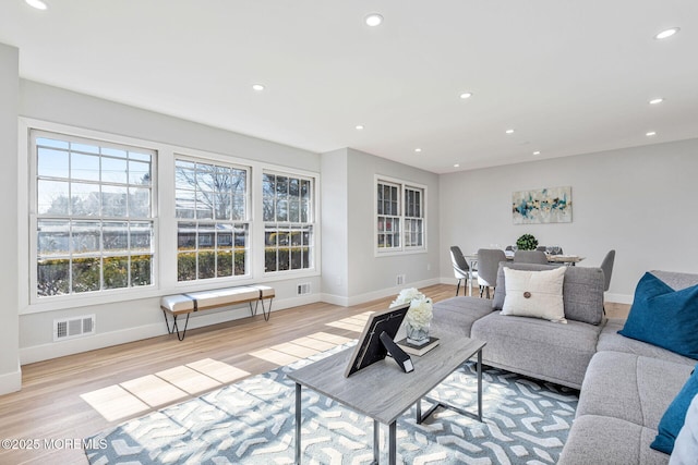 living room with baseboards, light wood finished floors, visible vents, and recessed lighting