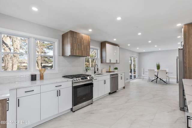 kitchen featuring marble finish floor, stainless steel appliances, recessed lighting, tasteful backsplash, and a sink