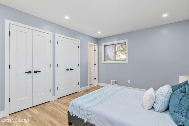 bedroom featuring recessed lighting, visible vents, baseboards, light wood-style floors, and two closets