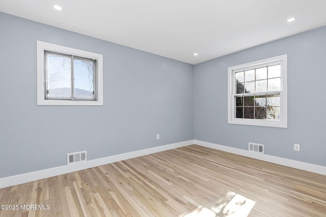 unfurnished room featuring visible vents, light wood finished floors, and baseboards