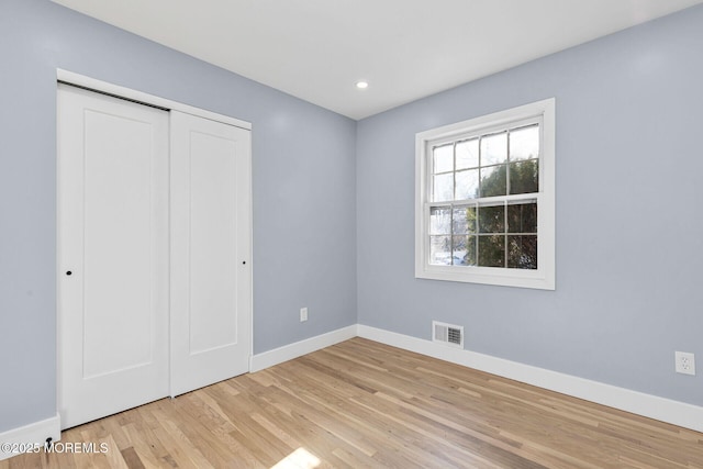 unfurnished bedroom with recessed lighting, a closet, visible vents, wood finished floors, and baseboards