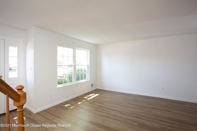 unfurnished room featuring a wealth of natural light, baseboards, and wood finished floors