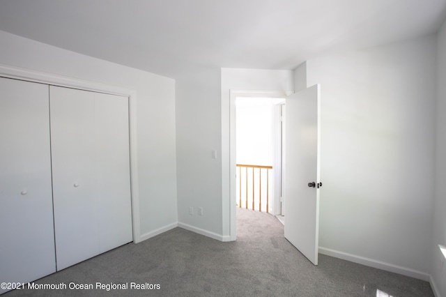 unfurnished bedroom with a closet, carpet, and baseboards